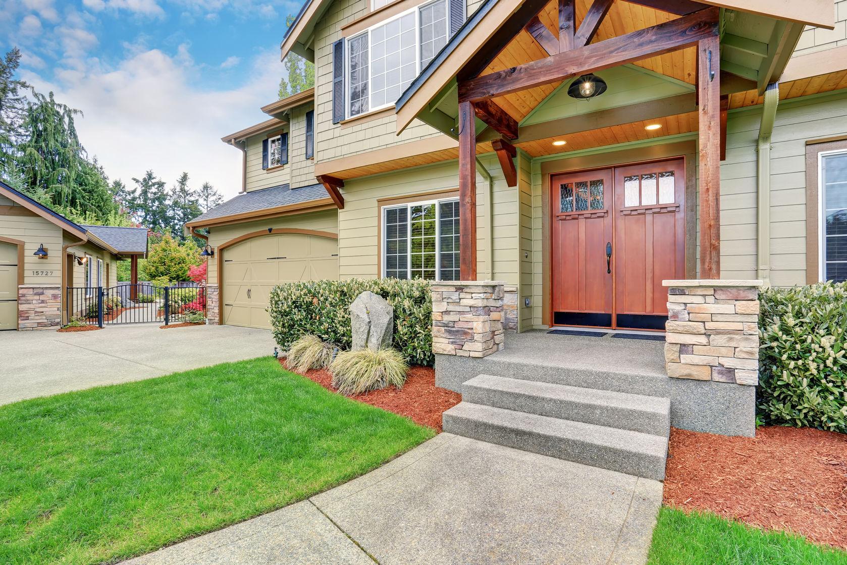 59956885 - view of house entrance with concrete walkway, stone column trim and double doors.