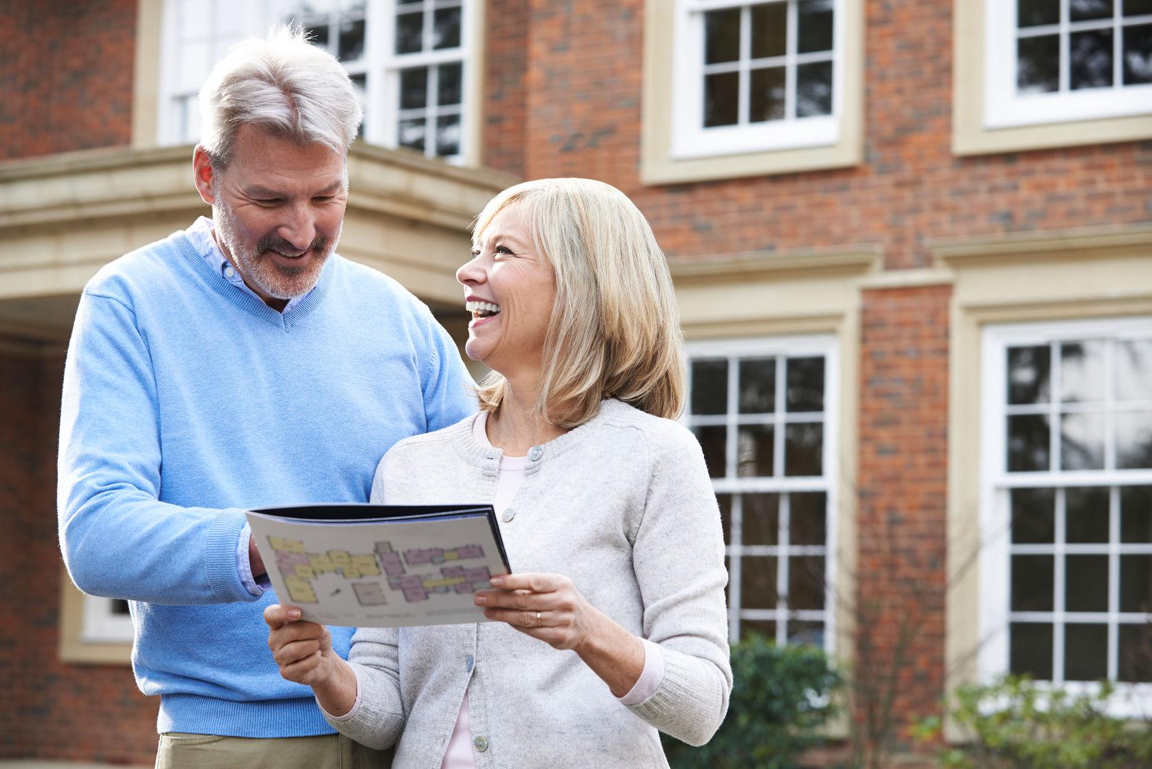 66192659 - mature couple standing outside house looking at property details