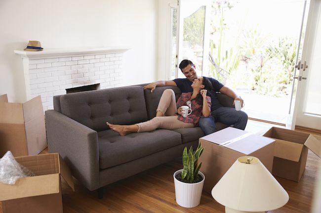 Couple on sofa with packing boxes around them.