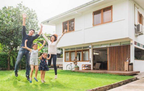 Young happy family in front of new house.