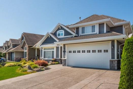 Blue house with stone and cement paved driveway.