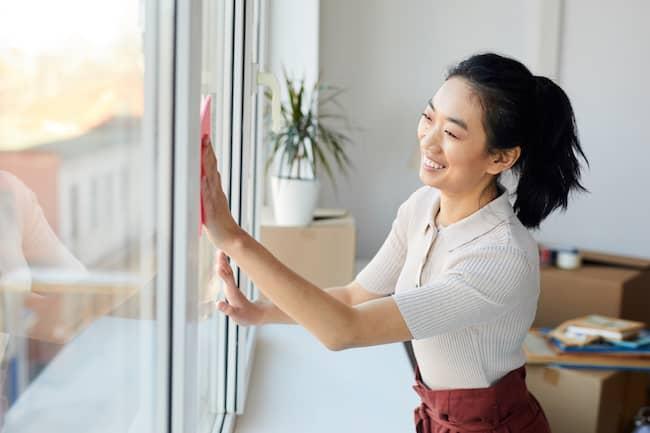 Woman cleaning window with packing boxes behind her