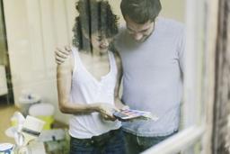 Young couple painting their apartment. They are looking at a color swatch.