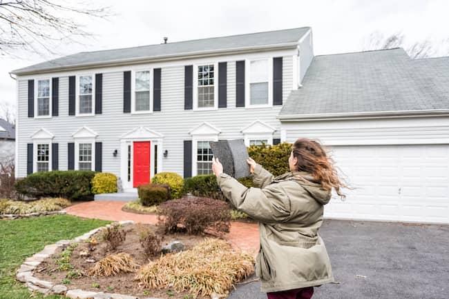Woman comparing roofing colors to existing roof on home
