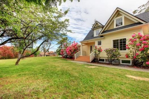 Yellow house with nice yard and landscaping.
