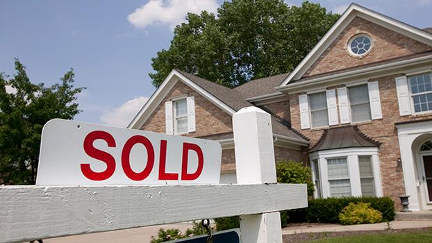 Sold house sign in Midwest suburban setting. Focus on sign.